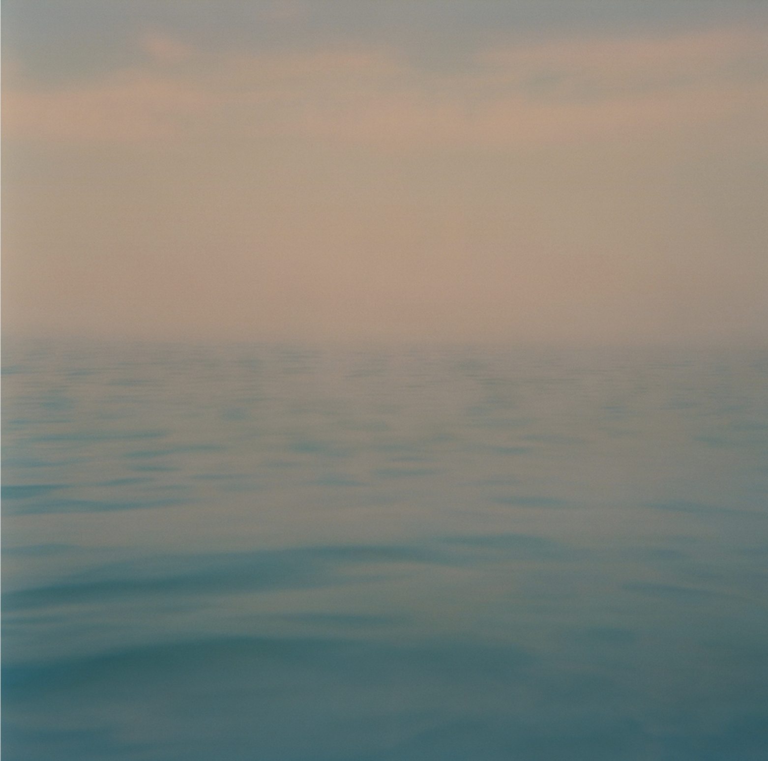 A soft, hazy horizon over calm blue water